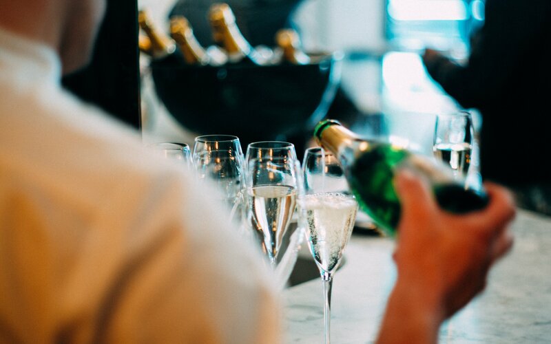 a person pours sparkling wine