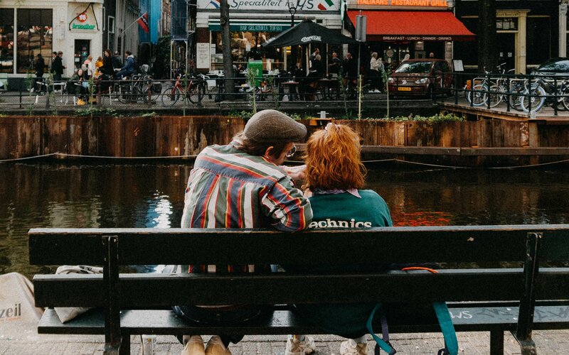 Two people sit on a bench 